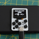 The Arduboy Mini perched atop a much larger battery pack which it's connected to with a USB-C cable.